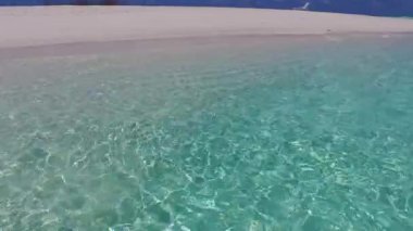 Mavi okyanus kıyısındaki dinlendirici tatil beldesi ve resifin yakınındaki parlak kum arka planının doğasını kapatın.