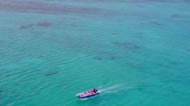 Dalgalara yakın beyaz kumlu arka planda, mavi sularda, rahatlatıcı ada plaj yaşam tarzının ılık manzarası.