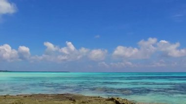 Deniz turizminin geniş açılı turizmi dalgaların yanında temiz kum arka planıyla mavi yeşil okyanusu aşıyor.