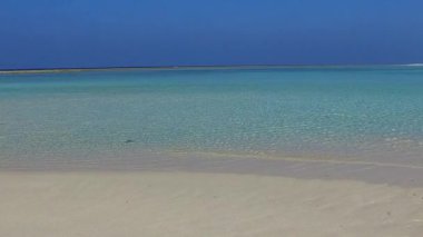 Mavi lagün ve beyaz kumlu arka planda gün batımından önce rahatlatıcı sahil macerasının güneşli manzarası