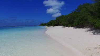 Plaj maceralarının güneşli turizmi deniz mavisi sularının kumsal kenarındaki beyaz kum arka planına sahiptir.