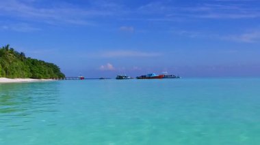 Lüks deniz kıyısı saatinin geniş açılı deniz manzarası berrak okyanus ve tatil köyü yakınlarında beyaz kumlu arka plan.