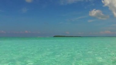 Huzurlu tatil beldesinin, tatil köyünün yakınındaki beyaz kum arka planlı mavi deniz kıyısındaki seyahatini kapatın.