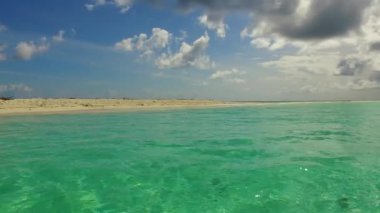 Gündüz vakti cennet sahili sahili manzarası sığ okyanus kıyısında, resifin yanında beyaz kumlu arka planda.