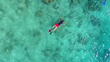 Mavi deniz kıyısında lüks sahil tatili panoraması ve dalgaların yanında beyaz kum arka planı.