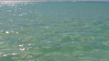 Mavi deniz kıyısında güzel bir göl tatili ve güneş ışığında beyaz kumlu bir arka plan.