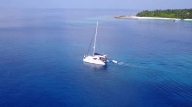 Turkuaz su ve dalgaların yakınındaki beyaz kum arka planıyla deniz kıyısı tatilinin ılık turizmi