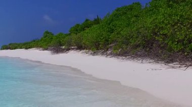 Sahil kenarındaki sakin sahil manzarasını kapatın. Mavi deniz kenarında, kumsalın yanında parlak kum arka planda.