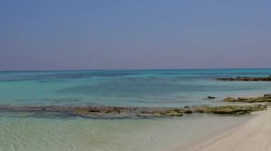 Şeffaf deniz ve dalgaların yakınındaki beyaz kumlu arka planda cennetteki göl saatinin romantik soyutlaması