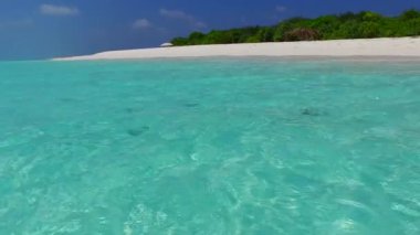 Mavi yeşil okyanus ve dalgaların yakınında beyaz kumlu arka plan ile huzurlu sahil tatilinin geniş açılı manzarası