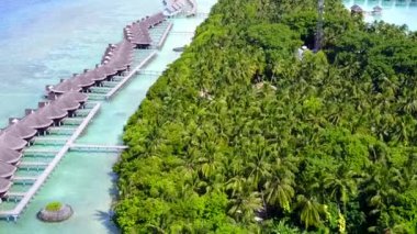 Mavi lagünün huzurlu turistik sahili dalgaların yanında beyaz kumlu arka planda.