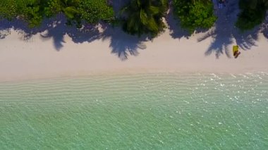 Lüks turist plaj gezisinin geniş açılı manzarası açık deniz kenarında, dalgaların yanında beyaz kum arka planda.