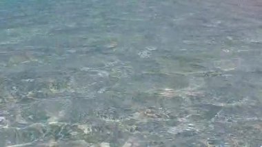 Mavi okyanus kıyısındaki turist plajı ve tatil köyü yakınlarındaki beyaz kumlu arka plan manzarasını kapatın.