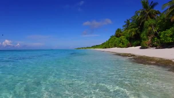 Tropikal adanın güneşli manzarası berrak denizi aşıp tatil köyü yakınlarındaki kumlu zemini temizler. — Stok video