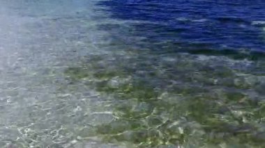 Sakin sahil plajının doğasını kopyalayın. Mavi okyanusu aşın. Beyaz kumlu arka planda tatil köyü var.