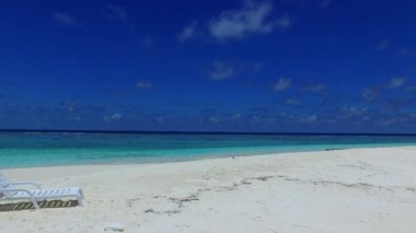 Lüks sahil yolculuğunun boş gökyüzü resifin yakınındaki parlak kum arka planına sahip mavi deniz kıyısında.