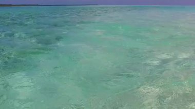 Turkuaz denizinin mükemmel sahil gezisinin güneşli dokusu, gün batımından önce beyaz kumlu arka planda.