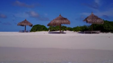 Şeffaf deniz kıyısında, kayalıkların yanında beyaz kumlu arka planda, rahatlatıcı tatil manzarası