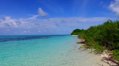 Lüks tatil köyünün geniş açılı gökyüzü kumsalın yakınındaki beyaz kum arka planlı mavi yeşil okyanus manzaralı plaj macerası.