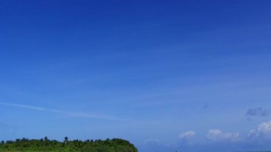 Mavi yeşil okyanus ve güneş doğduktan sonra beyaz kumlu arkaplan yoluyla huzurlu sahil seyahatinin geniş açılı manzarası