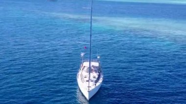 Mavi deniz kıyısındaki tropikal sahil yolculuğu ve dalgaların yakınındaki beyaz kumlu arka plan.