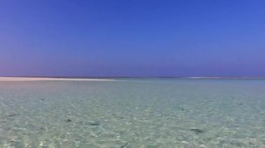 Su mavisi deniz ve tatil köyü yakınlarındaki beyaz kumlu arka planda rahatlatıcı sahil seyahatinin doğasını kapatın.