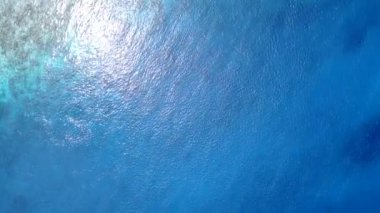 Deniz kıyısı turizminin geniş açılı turizmi mavi deniz kenarında ve beyaz kumlu arka planda sörf yapıyor.