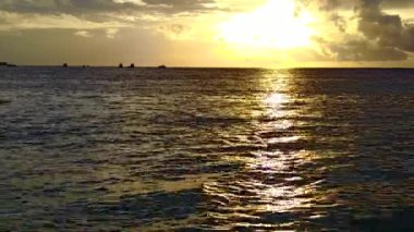 Mavi sularda tropikal sahil yolculuğunun romantik doğası ve sörfün yanında beyaz kumlu arka plan