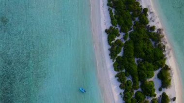 Cennet sahil şeridinde güneş batmadan önce beyaz kumlu arka planda mavi lagünün olduğu geniş açılı bir sahil gezisi.