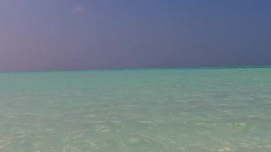 Berrak okyanus ve beyaz kumlu arka plandaki tropikal sahil yolculuğunun güneşli manzarası.