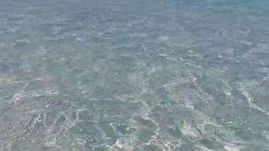 Mavi deniz kıyısında güneşli sahil yolculuğu ve tatil köyü yakınlarındaki beyaz kumlu arka plan.