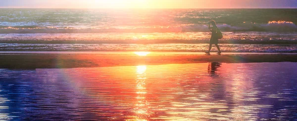 Akşam plaj. Gün batımında sahilde bir adamdır.