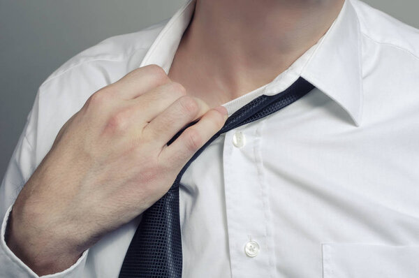 Man in white shirt taking off necktie