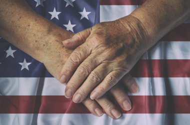 Yaşlı kadının elleri ile Amerikan bayrağı, üstten görünüm.