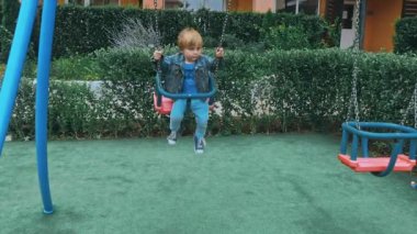 Küçük tatlı çocuk zincirli salıncaklarda eğleniyor..
