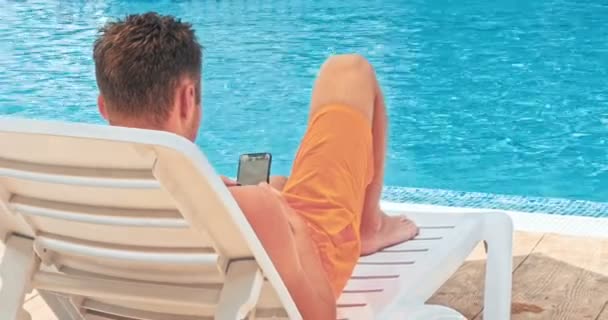 Man Hålla Mobiltelefonen Medan Kopplar Vid Poolen — Stockvideo