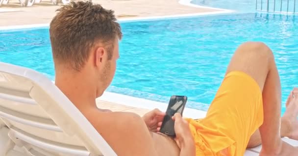 Ung Man Kopplar Vid Poolen Med Hjälp Mobiltelefon Arbete Och — Stockvideo