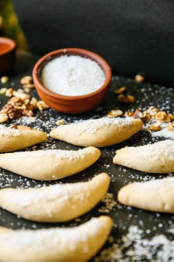 Üzerinde pudra şekeri olan çeşitli kurabiyelerle kaplı bir masa..