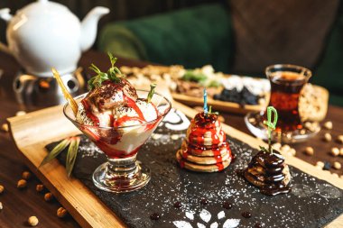 Tahta bir kesme tahtasının üstüne düzgünce yerleştirilmiş çeşitli tatlılarla dolu bir masa..