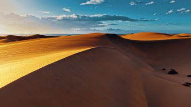 Gran Canaria 'nın altın kum tepelerinin üzerinde süzülen bu nefes kesici manzara berrak mavi gökyüzü altında canlı renkler sergiliyor ve adanın doğal güzelliğini gözler önüne seriyor..