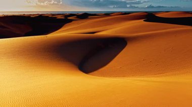 Gran Canaria 'daki altın kum tepeleri alacakaranlığın ılık ışığını yansıtarak çarpıcı bir manzara yaratıyor. Huzurlu ortam adanın eşsiz coğrafyası ve güzelliğini vurguluyor..