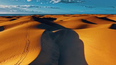 Büyük Kanarya 'da güneş ışığı altında büyük altın kum tepecikleri dalgalanır, çöl bölgelerini andıran kurak bir manzarayı sergiler..