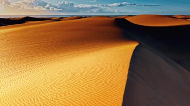Gran Canaria 'nın altın kum tepeleri renkli gökyüzünün altında uzanır ve bu İspanyol adasının altın saatindeki dingin güzelliğini yakalar. Doğanın kalıpları bellidir..