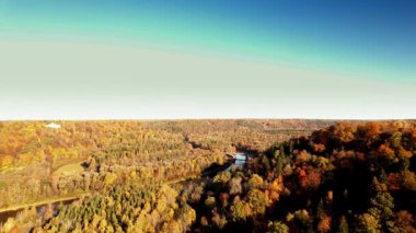 Manzara, sonbahar mevsiminde doğanın güzelliğini vurgulayan renkli sonbahar ağaçları ve dolambaçlı bir nehrin çarpıcı hava manzarasını sergiliyor..