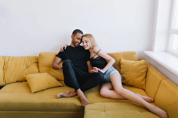 Couple hugging with eyes closed on the couch. Lovers holding hands, hugging. Happy faces, warm relationship, love, romance..