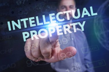 İş, teknoloji, internet ve şebeke kavramı. Genç bir girişimci geleceğin sanal ekranı üzerinde çalışıyor ve yazıyı görüyor: fikri mülkiyet