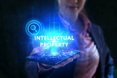 İş, teknoloji, internet ve şebeke kavramı. Genç bir girişimci geleceğin sanal ekranı üzerinde çalışıyor ve yazıyı görüyor: fikri mülkiyet