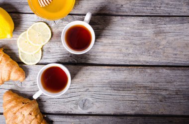 Zencefil, kruvasan ve ahşap zemin üzerine limon ile çay