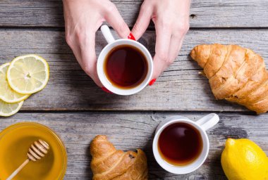 Çay limon ve kruvasan tutan kadın el