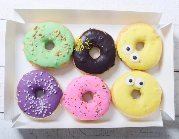 Colorful baked donuts in box . Top view
